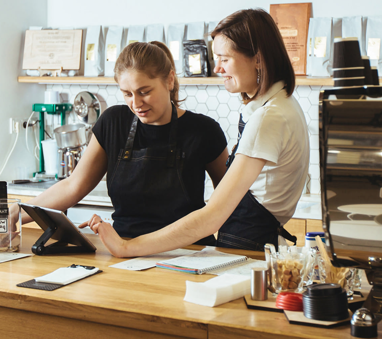 Two baristas handling customer payments and orders on tablet
